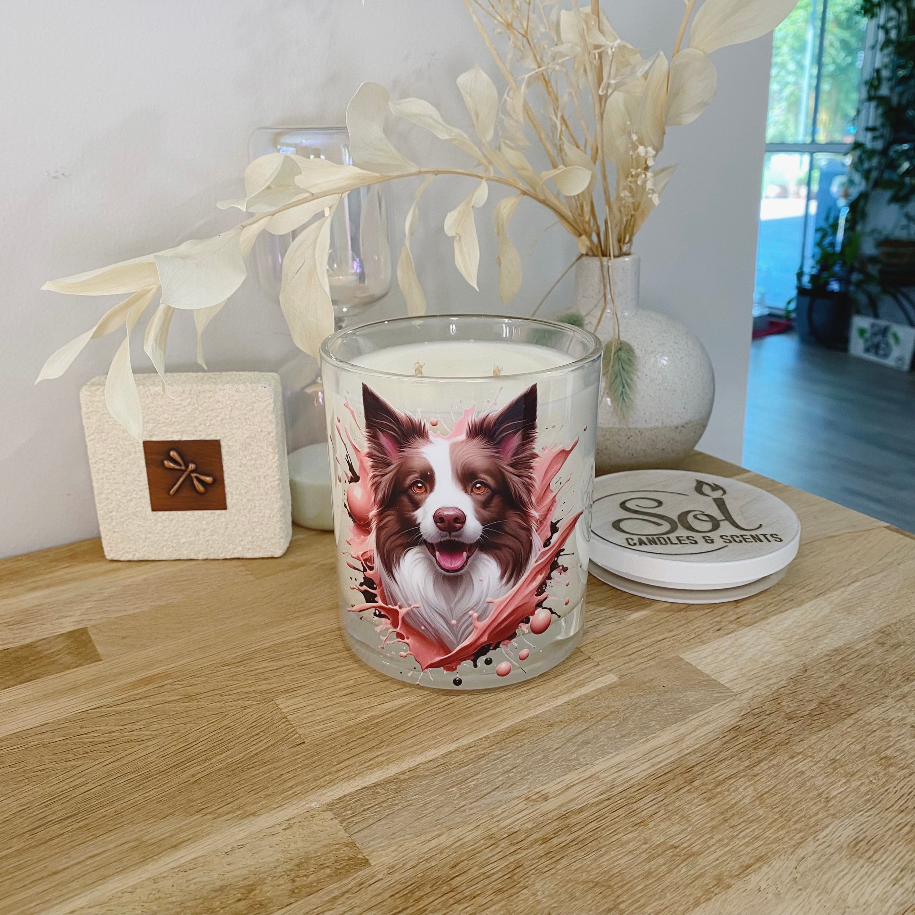 Candle with a Border Collie dog design on a wooden table, featuring Sol Candles & Scents branding.
