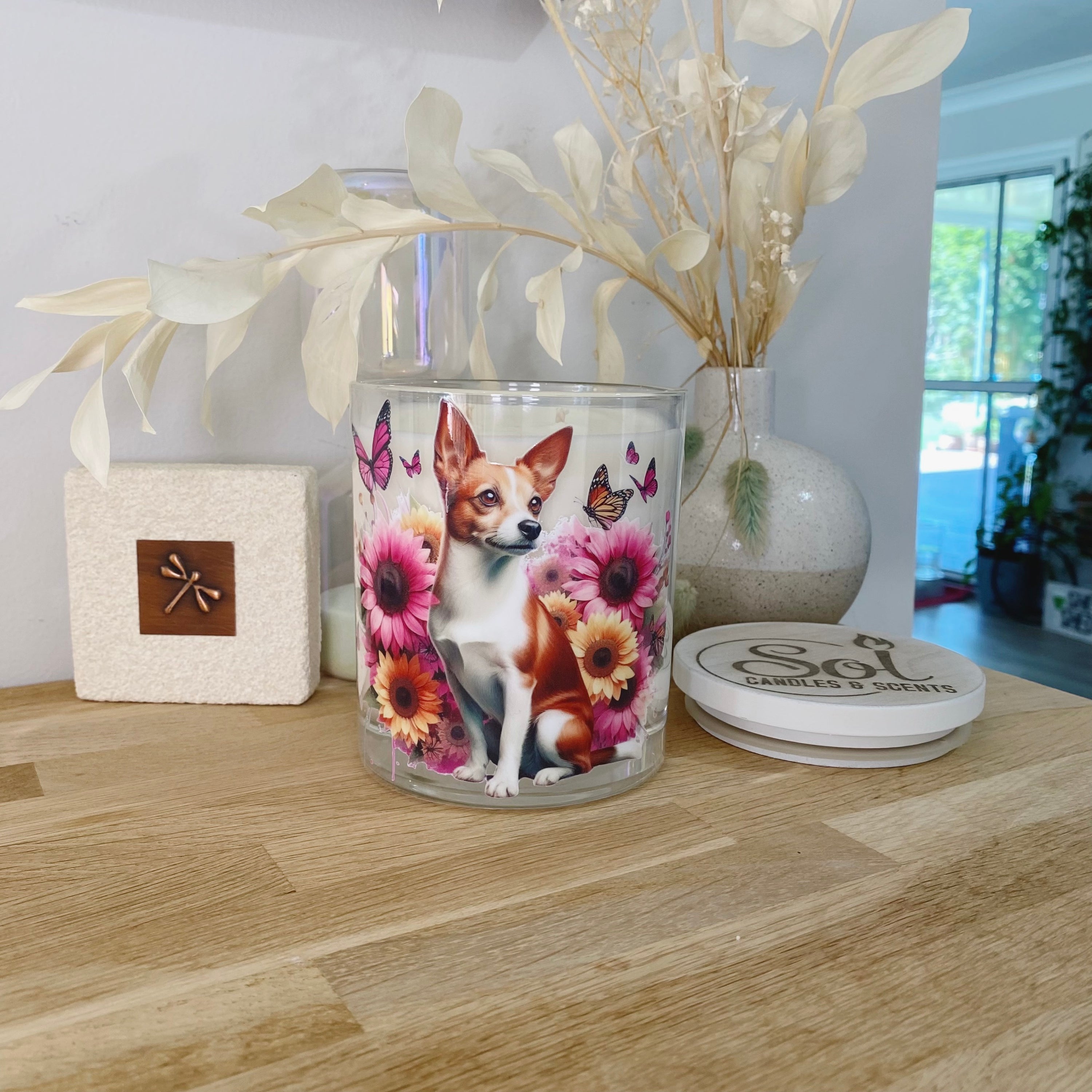 Candle with a Fox Terrior dog design on a wooden surface with decorative elements