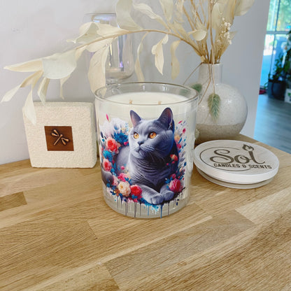 Candle with a cat design on a wooden surface, surrounded by decorative elements.