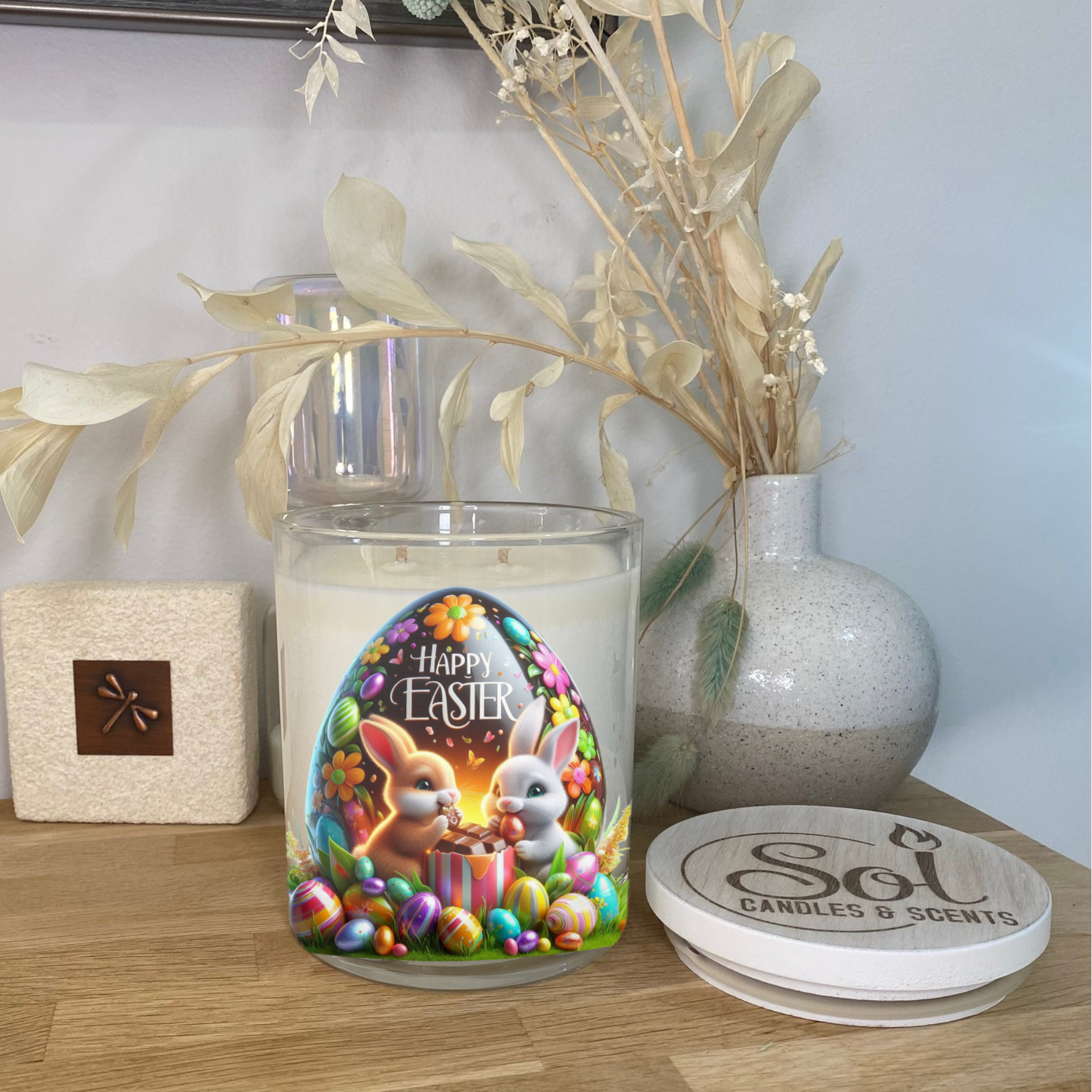 Easter-themed candle with rabbit design on a wooden surface, surrounded by decorative elements.