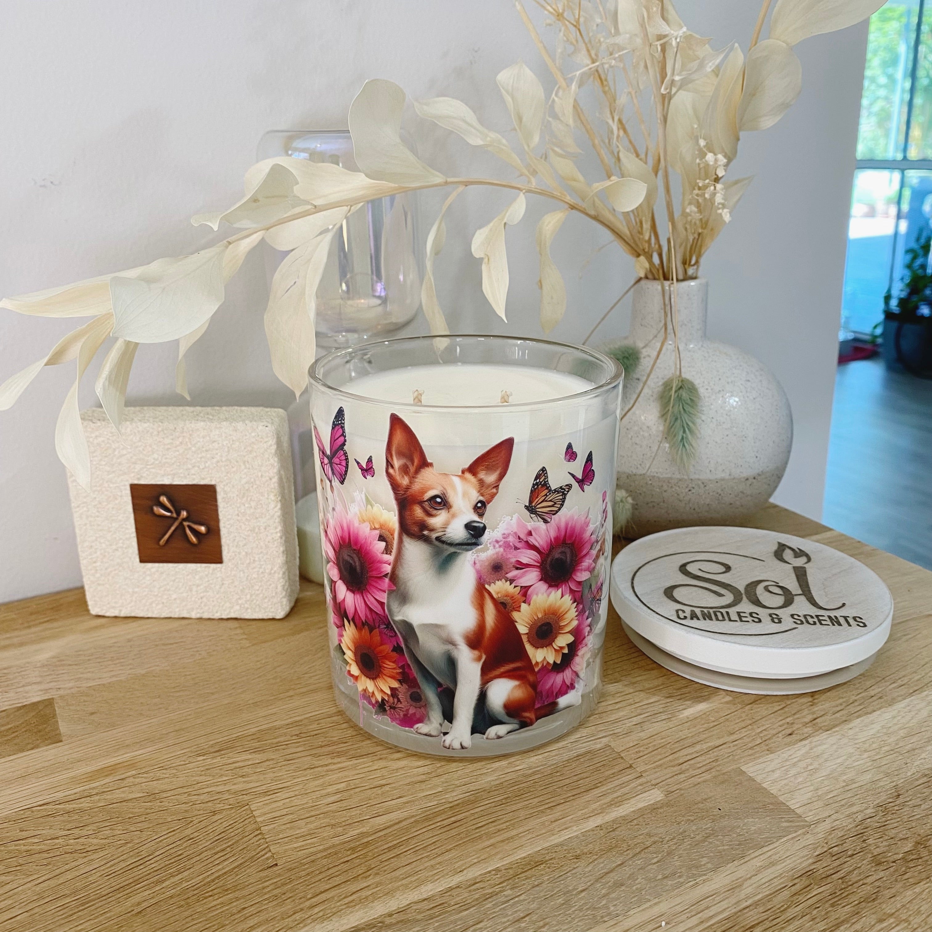 Candle with a dog design on a wooden surface, featuring &